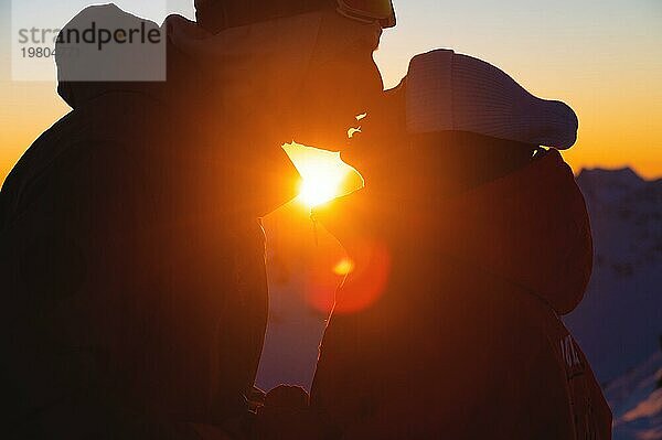 Silhouette eines Paares  das sich vor dem Hintergrund des Sonnenuntergangs küsst. Silhouette eines jungen Paares  das sich vor dem Hintergrund des Sonnenuntergangs liebt. Verliebtes Pärchen bei Sonnenuntergang in den Bergen