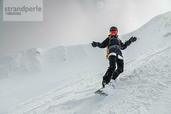 Junges stilvolles Mädchen oder Frau in Bewegung Snowboarding in den Bergen