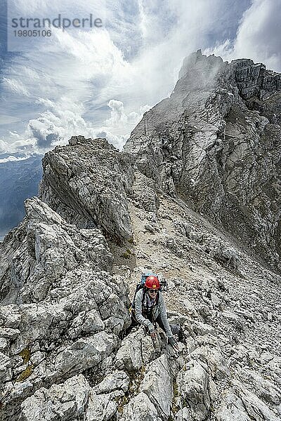 Bergsteigerin klettert auf einem schmalen felsigen Berggrat  Watzmann Überschreitung zur Watzmann Mittelspitze  Nationalpark Berchtesgaden  Berchtesgadener Alpen  Bayern  Deutschland  Europa