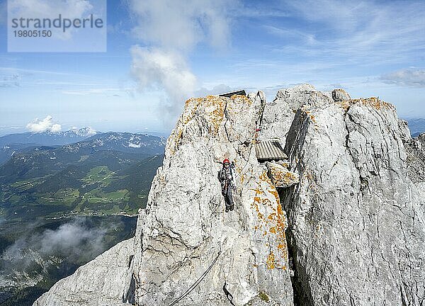 Bergsteigerin klettert in einem mit Stahlseil gesicherten Klettersteig  schmaler felsiger Berggrat  Watzmann Überschreitung zur Watzmann Mittelspitze  Nationalpark Berchtesgaden  Berchtesgadener Alpen  Bayern  Deutschland  Europa