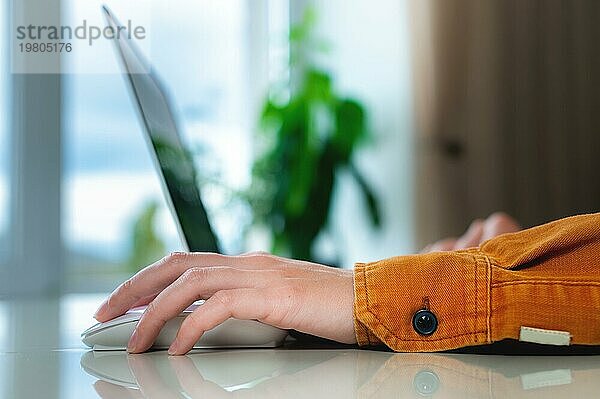 Häusliche Umgebung  Frauenhand ruht auf Laptopmaus Arbeit von zu Hause aus