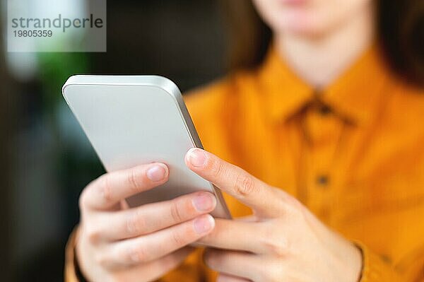 Hipster Mädchen benutzt ein Mobiltelefon. Close up weibliche Hände halten ein Gadget auf einem unscharfen Hintergrund