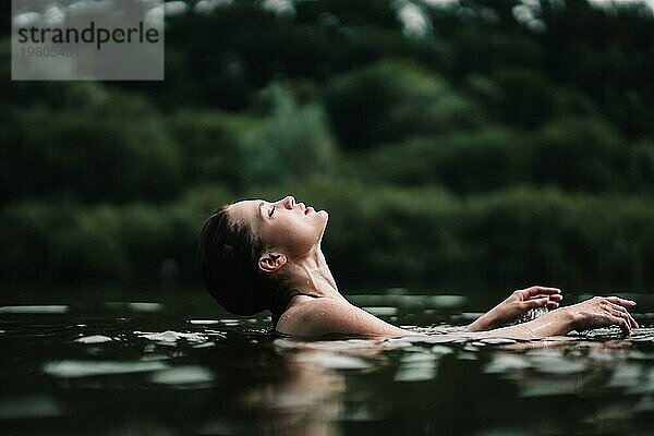 Ein junges  schlankes  schönes und heißes Mädchen mit nassen Haaren schwimmt im See  reist zu Wasserfällen  entspannt sich am See