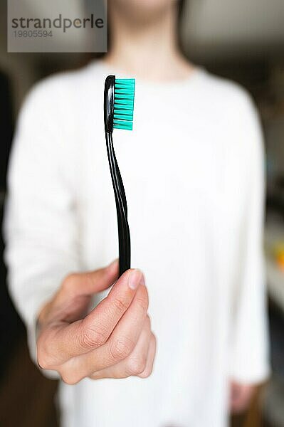 Frau hält eine Zahnbürste im Vordergrund scharf  Hintergrund unscharf. Mundhygiene