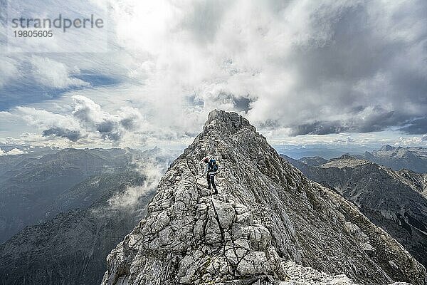 Bergsteigerin auf einem schmalen felsigen Berggrat  Watzmann Überschreitung zur Watzmann Mittelspitze  Ausblick auf Bergpanorama mit Steinernes Meer  Nationalpark Berchtesgaden  Berchtesgadener Alpen  Bayern  Deutschland  Europa