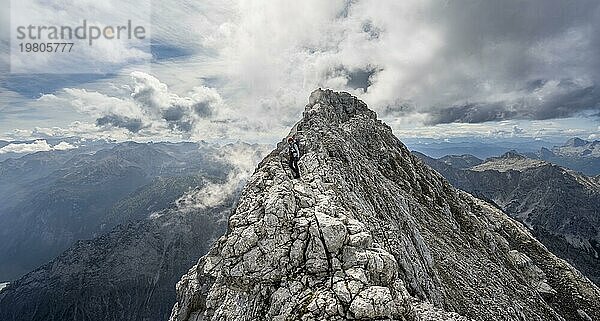 Bergsteigerin auf einem schmalen felsigen Berggrat  Watzmann Überschreitung zur Watzmann Mittelspitze  Ausblick auf Bergpanorama mit Steinernes Meer  Nationalpark Berchtesgaden  Berchtesgadener Alpen  Bayern  Deutschland  Europa