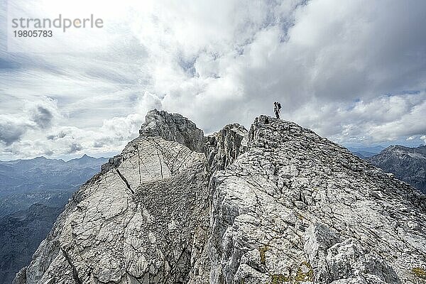 Bergsteigerin auf einem schmalen felsigen Berggrat  Watzmann Überschreitung zur Watzmann Mittelspitze  Ausblick auf Bergpanorama mit Steinernes Meer  Nationalpark Berchtesgaden  Berchtesgadener Alpen  Bayern  Deutschland  Europa