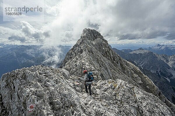 Bergsteigerin auf einem schmalen felsigen Berggrat  Watzmann Überschreitung zur Watzmann Mittelspitze  Ausblick auf Bergpanorama mit Steinernes Meer  Nationalpark Berchtesgaden  Berchtesgadener Alpen  Bayern  Deutschland  Europa