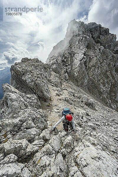 Bergsteigerin klettert auf einem schmalen felsigen Berggrat  Watzmann Überschreitung zur Watzmann Mittelspitze  Nationalpark Berchtesgaden  Berchtesgadener Alpen  Bayern  Deutschland  Europa