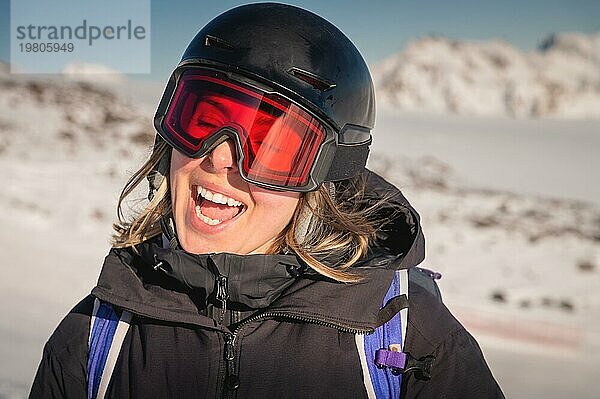 Porträt einer Frau in den Alpen. Lächelnde junge Frau mit Skibrille und Helm beim Skifahren im Skigebiet angehalten