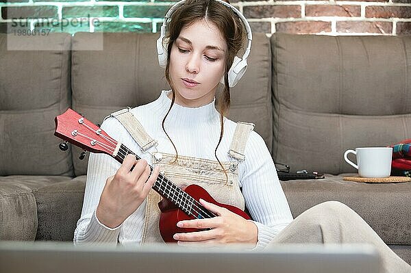 Junge Studentin  die zu Hause Ukulele spielen lernt  Fernunterricht für Gesang und Musikinstrumente