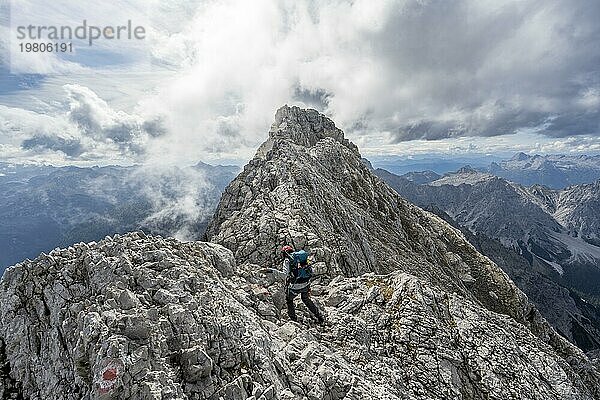 Bergsteigerin auf einem schmalen felsigen Berggrat  Watzmann Überschreitung zur Watzmann Mittelspitze  Ausblick auf Bergpanorama mit Steinernes Meer  Nationalpark Berchtesgaden  Berchtesgadener Alpen  Bayern  Deutschland  Europa