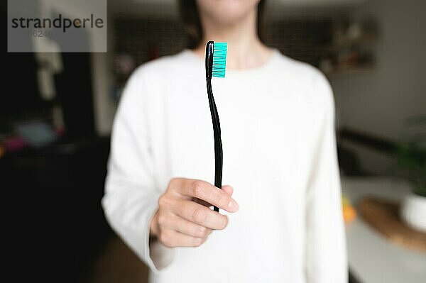 Frau hält eine Zahnbürste im Vordergrund scharf  Hintergrund unscharf. Mundhygiene