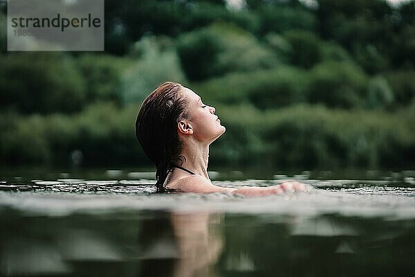 Ein junges  schlankes  schönes und heißes Mädchen mit nassen Haaren und großen Lippen schwimmt im See  reist zu Wasserfällen  entspannt sich am See