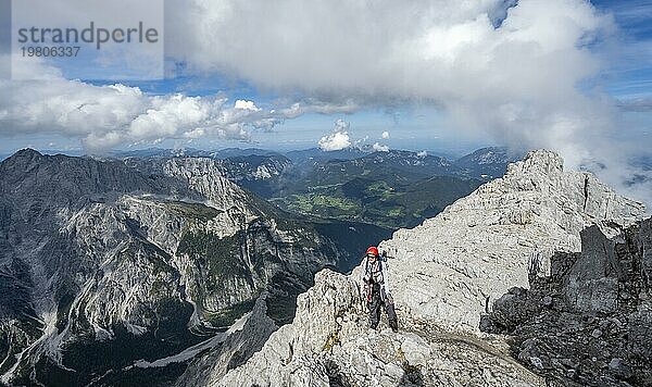 Bergsteigerin auf einem schmalen felsigen Berggrat  Ausblick auf Bergpanorama mit Hochkalter  Watzmann Überschreitung zur Watzmann Mittelspitze  Nationalpark Berchtesgaden  Berchtesgadener Alpen  Bayern  Deutschland  Europa