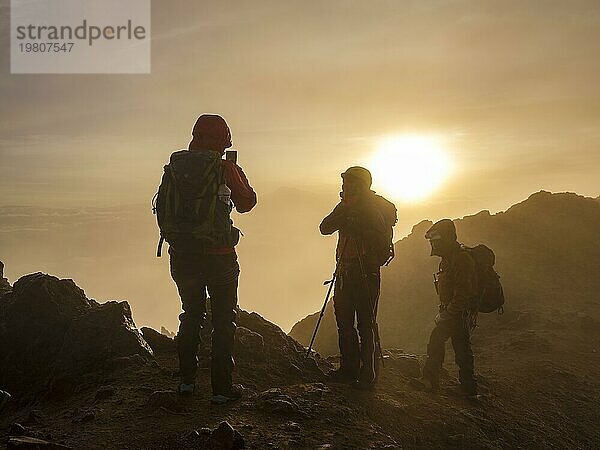 Bergsteiger fotografiert mit dem Handy im Nebel bei Sonnenaufgang  Iliniza Nord  Provinz Pichincha  Ecuador  Südamerika