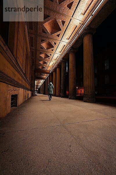 Eine einsame Person steht nachts zwischen großen Säulen unter Straßenbeleuchtung  Berlin  Deutschland  Europa