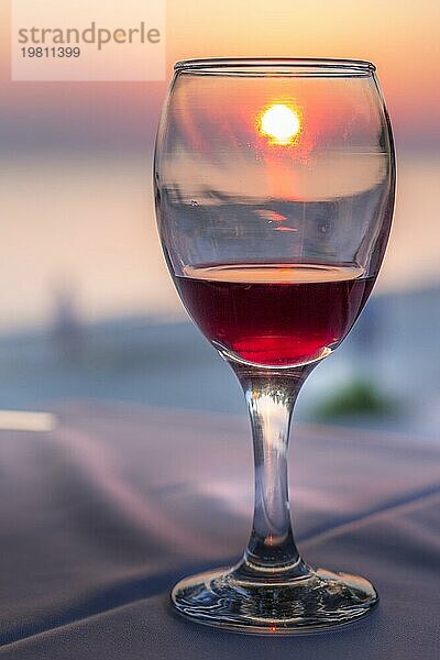 Romantisches Glas Wein. Sonnenuntergang am Strand reflektiert in Rotwein  Sommerurlaub Konzept