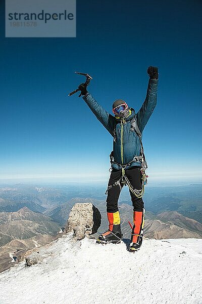 Professioneller Führer Wanderer auf dem Gipfel des Felsens mit erhobenen Händen freut sich über den nächsten Erfolg des Aufstiegs an einem sonnigen Nachmittag