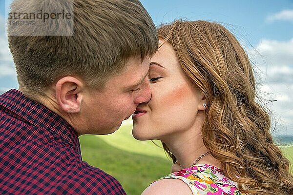 Junges Paar  das sich vor dem Hintergrund einer Sommerlandschaft küsst  Nahaufnahme