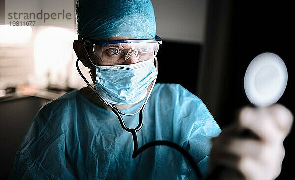 Männlicher Chirurg in Uniform bei der Arbeit mit einem Stethoskop in einer Arztpraxis