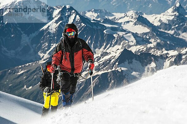 Der Bergsteiger erklimmt den schneebedeckten Gipfel. Das Konzept  Schwierigkeiten zu überwinden und das Ziel zu erreichen