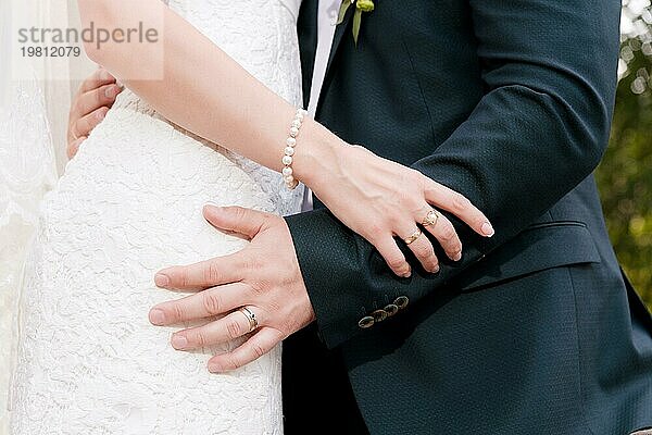 Nahaufnahme der Hände in Umarmungen von Jungvermählten am Hochzeitstag. Das Konzept der Hochzeit Glück und Zärtlichkeit