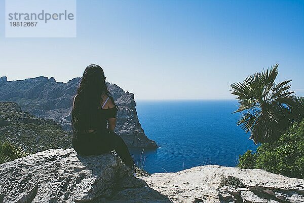 Schönes Porträt einer jungen lateinischen Frau in schwarz gekleidet vor dem Meer