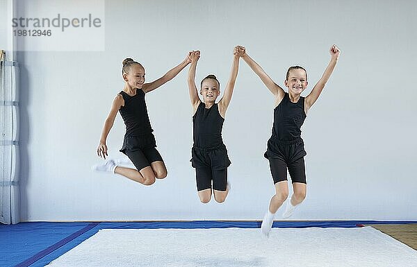 Gruppe von fröhlichen Kindern springen in der Turnhalle. Gymnastik Konzept. Gemischte Medien