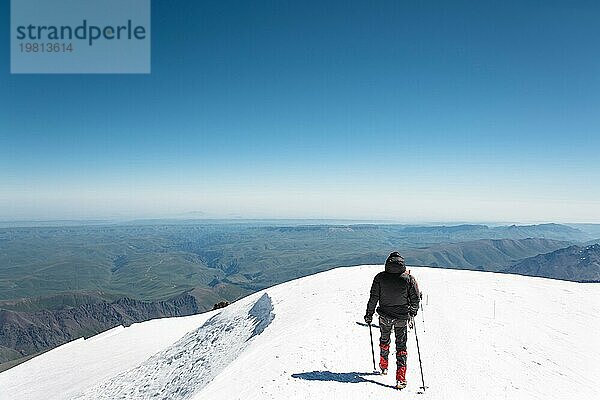 Professionelle Bergsteiger besteigen den westlichen Gipfel des Elbrus vor dem Hintergrund des kaukasischen Gebirgskamms und der schneebedeckten Gipfel des Kaukasusgebirges