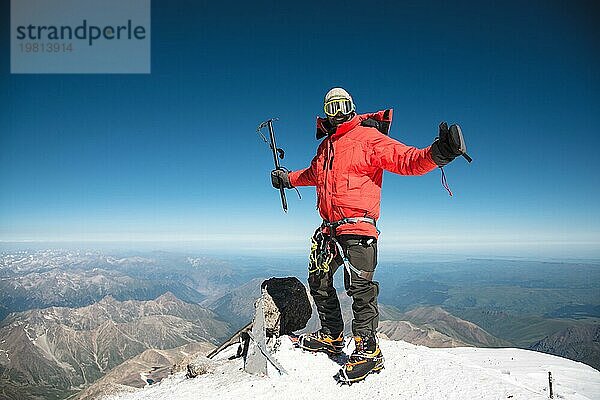 Profi Wanderer auf dem Gipfel des Felsens mit erhobenen Händen freut sich über den nächsten Sieg des Aufstiegs an einem sonnigen Nachmittag