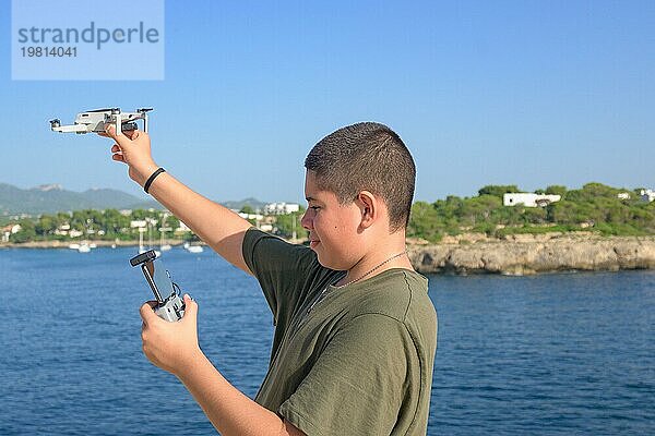 Porträt glücklicher Teenager  Vorbereitung und Abschluss des Fluges Details für Drohne Flug  Mittelmeer Hintergrund an einem sonnigen Tag  Technologiekonzept Spanien  Balearen