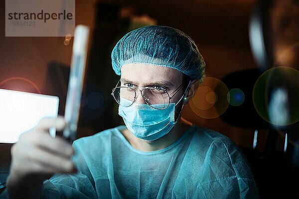 Wissenschaftlicher Arzt in einem dunklen Labor mit einem Reagenzglas mit einem Arzneimittel
