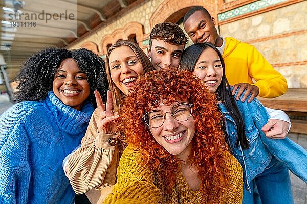Verschiedene junge Freunde machen ein Selfie und lächeln und gestikulieren erfolgreich in einem städtischen Raum