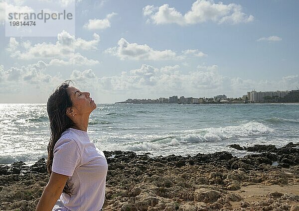 Entspannte Frau atmet frische Luft auf den Felsen am Mittelmeer