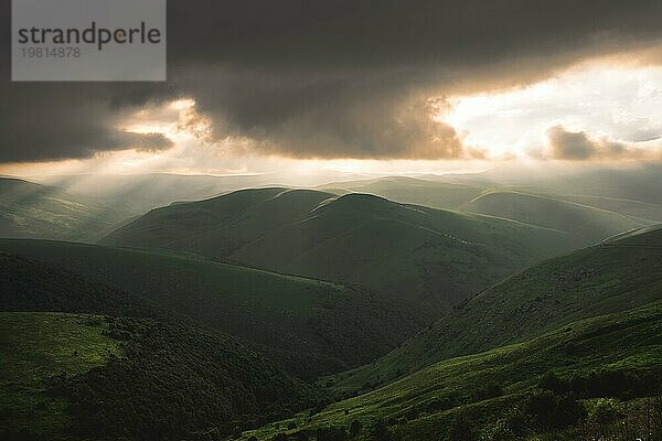 Schöne kaukasischen hügeligen grünen Tälern mit niedrigen Wolken und Strahlen der untergehenden Sonne. Schöne Sommer Sonnenuntergang Landschaft