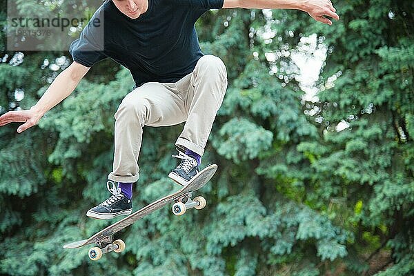 Langhaariger Skater Teenager in TShirt und Turnschuhmütze springt den Ollie vor dem Hintergrund eines stürmischen Himmels über der Stadt