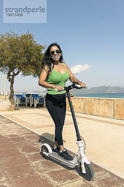 Frau reitet Elektroroller  glücklich und Sommer Fahrt auf tropischen Insel Strand Resort für Urlaub. Stadt  Straße und umweltfreundliche Transport  Spaß auf escooter im Urlaub in Mallorca  Baleareninsel