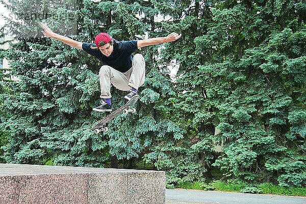 Langhaariger Skater Teenager in TShirt und Turnschuhmütze springt den Ollie vor dem Hintergrund eines stürmischen Himmels über der Stadt