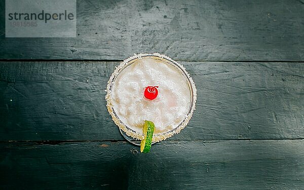 Draufsicht auf einen köstlichen gefrorenen Kokosnusscocktail mit Kirsche. Kokosnuss Margarita mit Kirsche auf Holztisch
