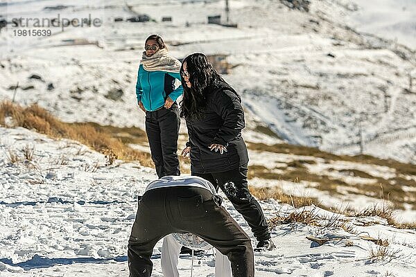 Drei junge Latinos spielen im Schnee in den Bergen von Sierra Nevada