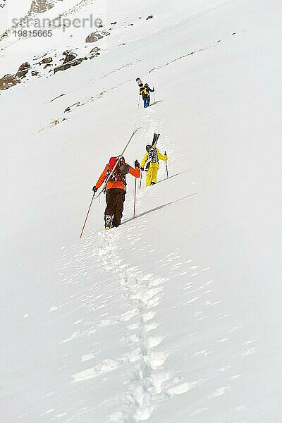 Zwei Ski Freerider klettern den Hang im Tiefschnee hinauf  die Ausrüstung auf dem Rücken am Rucksack befestigt. Das Konzept des Winter Extremsports