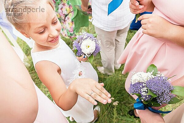 Kleine süße Freundin der Braut prahlt mit ihren Ringen vor erwachsenen Freundinnen bei der Ausgangsanmeldung