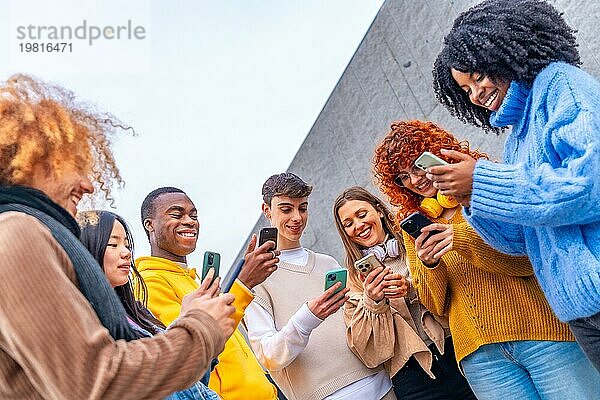 Niedriger Blickwinkel auf eine Gruppe von Freunden  die in der Stadt telefonieren