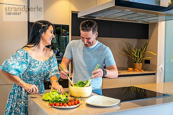 Ein glückliches Paar in seinem neuen Zuhause  das gemeinsam einen gesunden Salat zubereitet