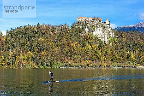Bled  Slowenien  31. Oktober 2018: Mann auf Paddle Board auf See Bled und Herbst bunten Bäumen Hintergrund  Europa