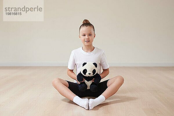 Nettes Mädchen Kind posiert im Studio mit einem Stofftier in einem hellen Studio. Das Konzept der Bildung  Tanz  Sport  Pilates  Stretching  gesunden Lebensstil. Gemischte Medien