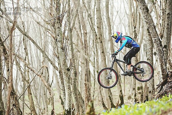 Ein Mountainbikefahrer springt von einem Sprungbrett in einem nebligen Wald  im Kaukasusgebirge  Downhill Fahrer