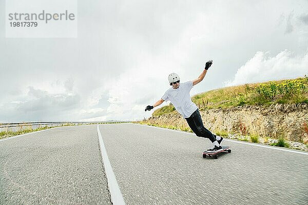 Der junge Mann führt einen komplexen Trick namens Slide auf dem Longboard aus