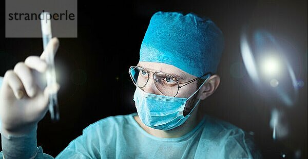 Wissenschaftlicher Arzt in einem dunklen Labor mit einem Reagenzglas mit einem Arzneimittel